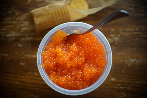 bright orange salmon eggs in a bowl with a spoon