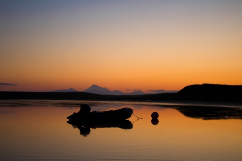 silhouette of a small skiff moored at a buoy at sunrise
