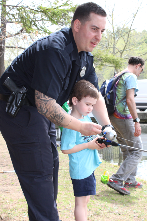 A policer officer helps a child reel in a fish