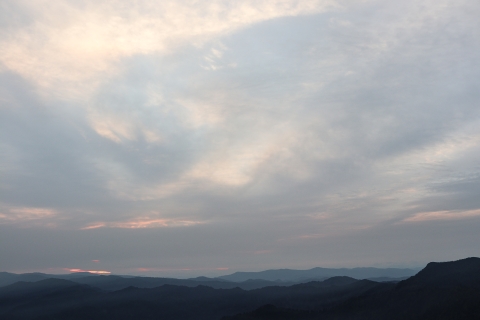 Rolling forested mountains and a cloud-filled sky