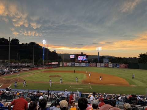 A photo of people playing baseball on a baseball field in the evening. 