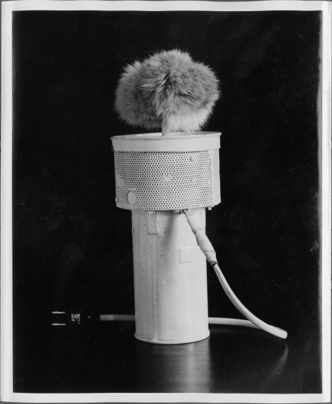 Device pictured (a "squeagler") features a cylindrical metal base, a wider and shorter cylindrical top made out of metal mesh, and surmounted by a "ball" of Rabbit fur. A cord with a two-prong plug (or plugging into an electrical outlet) is located just below the metal mesh portion of the device.