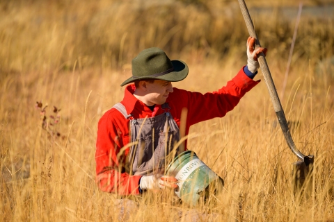 A volunteer holds a shovel after planting a tree as part of a habitat restoration project