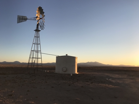 A water tank by a windmill on a ranch
