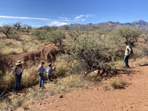 Four individuals stand near a dry river channel structure