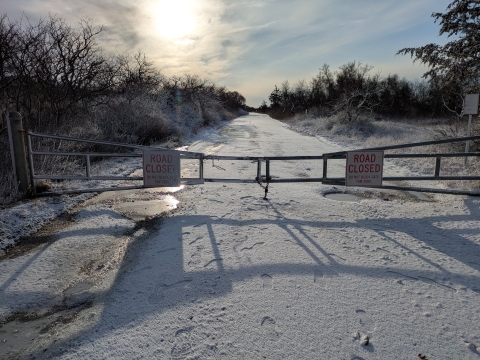 Image of closed gate over snowy road.