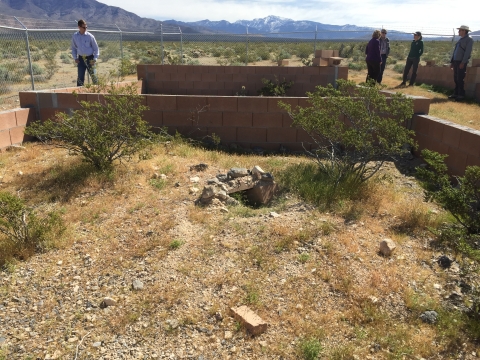 Short brick structures on a desert with 5 individuals standing by them