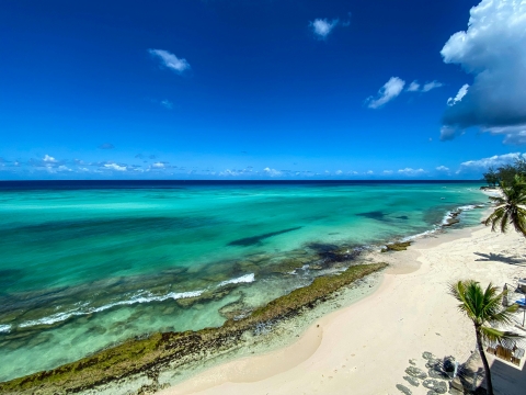 An aerial view of a white sand beach on turquoise waters with a blue sky overhead