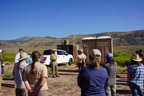 Conservation partners are led in a group discussion by two biologists as they prepare to enter a project site. 