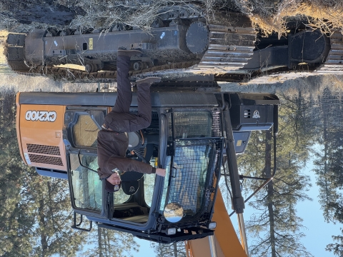 A FWS employee standing on an excavator