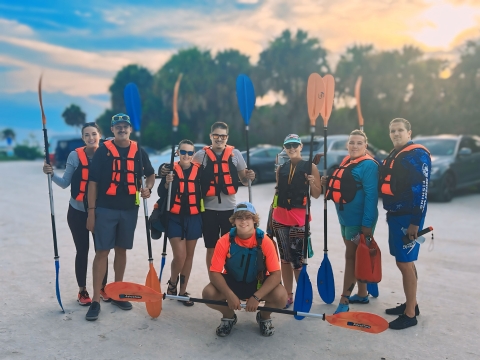 Participants in a guided kayak tour stand holding their paddles at Merritt Island Refuge in Florida.