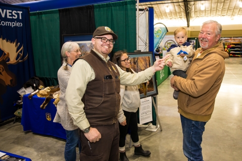 A ranger points at a small, stuffed blue goose being held by a youth participant