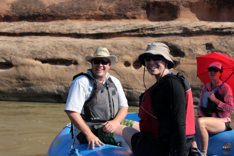 Three individuals float on a raft on a river