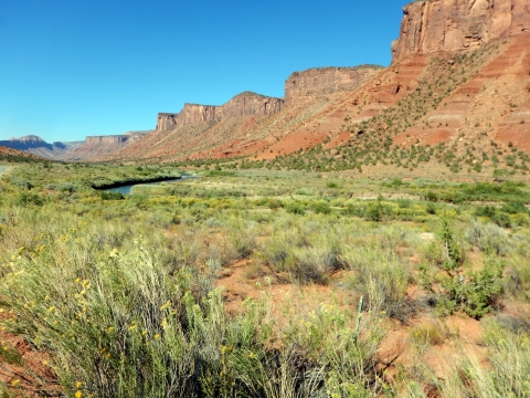 A grassland with backdrop of canyons and a river