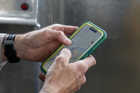 A close up of a phone with a map on it in the helm of a boat.