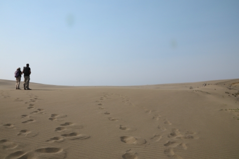 two people standing on sand under a blue sky