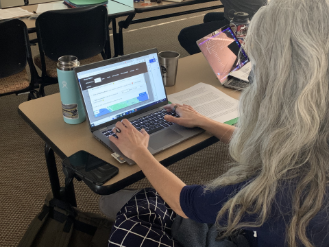 An individuals works on a laptop in a classroom