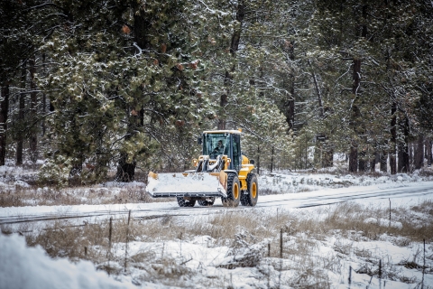A maintenance employee uses a front-end loader to clear snow from a road