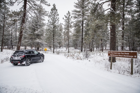 A car turns onto a snow covered auto tour route