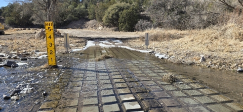 A desert stream vehicle crossing with concrete squares allowing water to pass.