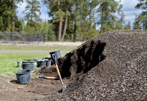 A shovel and pots sits next to a pile of dirt to be used potting trees for a nursery