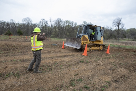 Bulldozer operator takes instruction from instructor on the ground