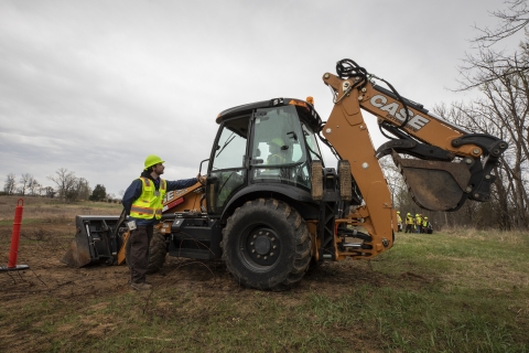 Backhoe tractor instructor teaches student about tractor