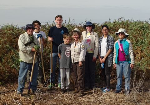 Group of people from all ages stand by a habitat restoration site.