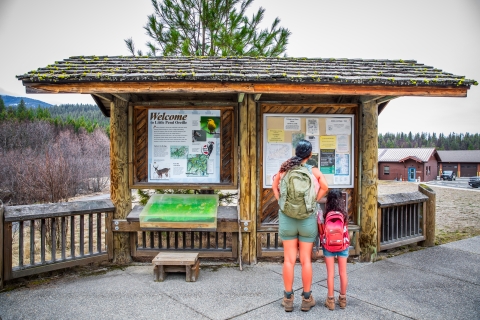 A woman and a child examine an interpretive kiosk