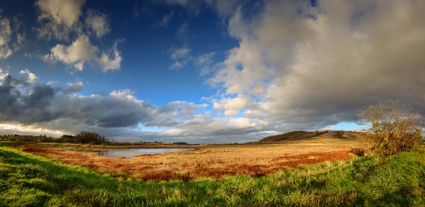 Cloudy sky overcasting a landscape of agricultural field and body of water