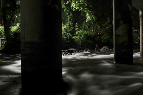 Person sitting under a bridge, in the dark, with night-vision glasses
