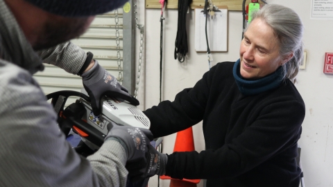 Two people working on a chainsaw