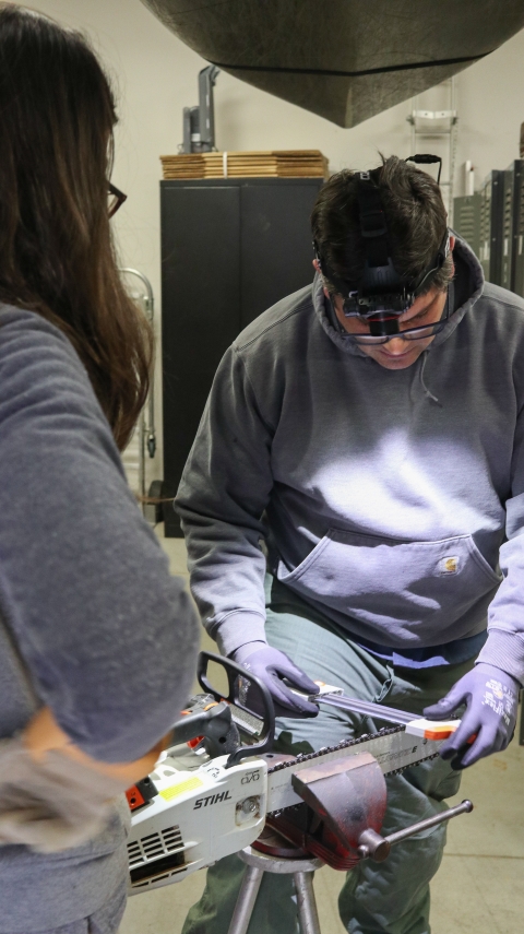 Man holding a tool up to a chainsaw chain