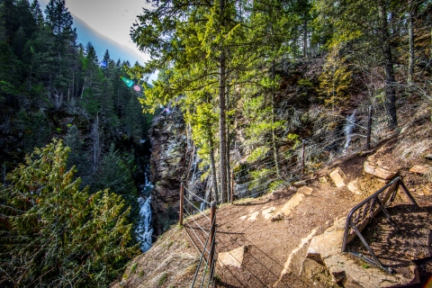 A small fence blocks a cliff, which overlooks a waterfall