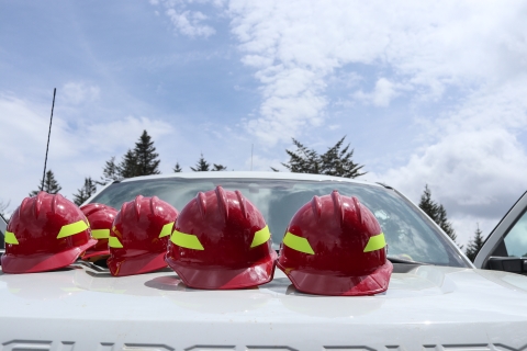 Five hard hats set out on the hood of a truck