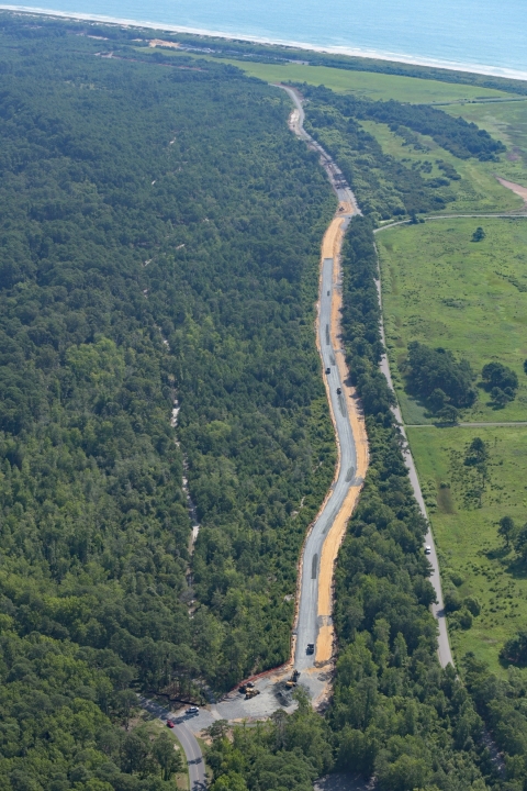 An aerial view of a road under construction that winds through the forest.