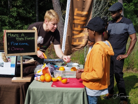 A volunteer helps a group of children with a nature craft