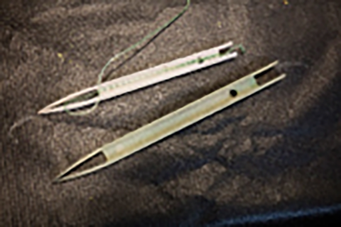 Two H-needles, the upper partially load with twine, the lower needle is empty.