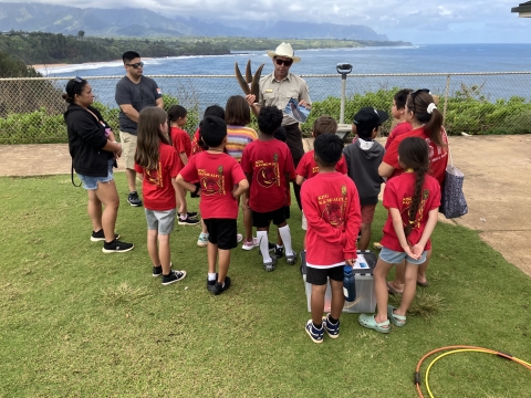A park ranger talks in front of a group of students overlooking the ocean from a bluff. 
