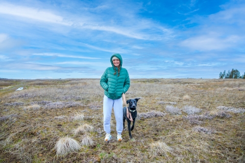 A woman stands with her dog in a prairie
