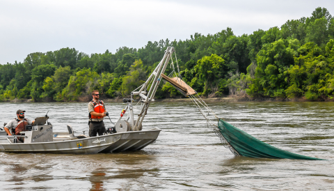 The trawl is being lowered into the water as the boom extends downward.