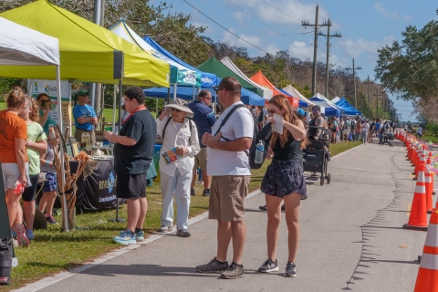 A busy scene with many people greeting exhibitors at different tents