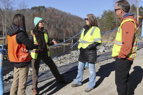 Four biologists in conversation with a river in he background