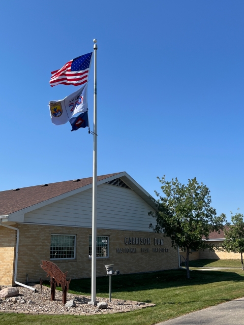 3 flags on flagpole with US flag atop USFWS ones