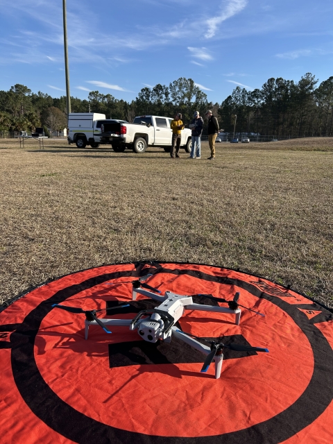 Skydio X10 on a red and black pad with people and a truck in the backgraound