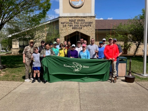 Group of people posing with fishing poles and banner