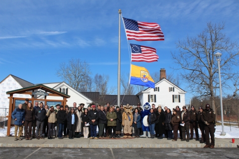 people pose at flagpole, under 2 US flags, USFWS one