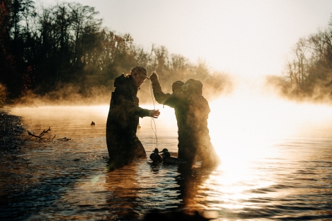 Waterfowl hunters in waders set up duck decoys in a North Carolina Wetland