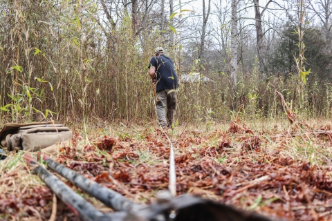 Man walking into the distance, holding one end of a measuring tape