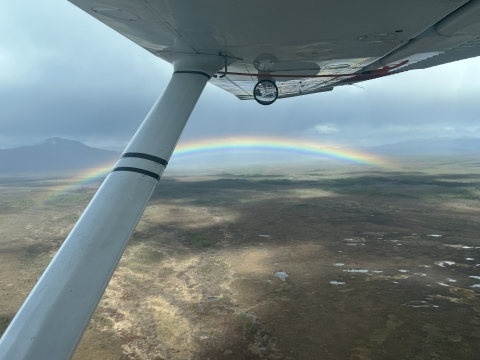 aerial view of a plane wing with a rainbow in the background